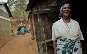 Martha Kimuyu Kinai in Machakos, Kenya, member of a women's group standing outside her house.