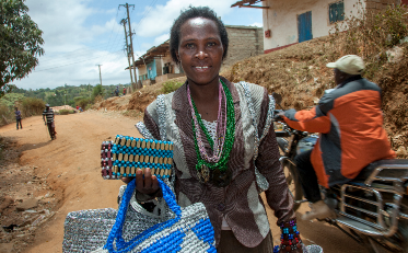 Benedetta Kalondu, basket maker in Tala, Kenya, carrying baskets.