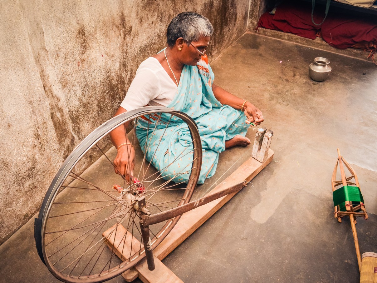 A women sitting on the floor weaving silk.