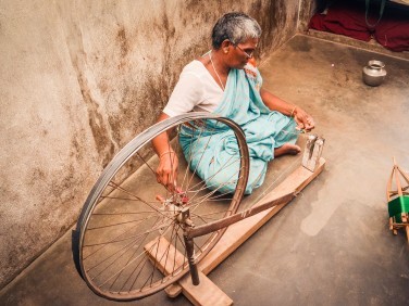 A women sitting on the floor weaving silk.