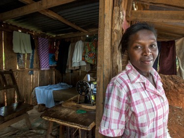 Hannah Haciku, a tailor from Nairobi, Kenya, standing outside her house