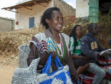 Benedetta Kalondu walking down a street with her baskets.