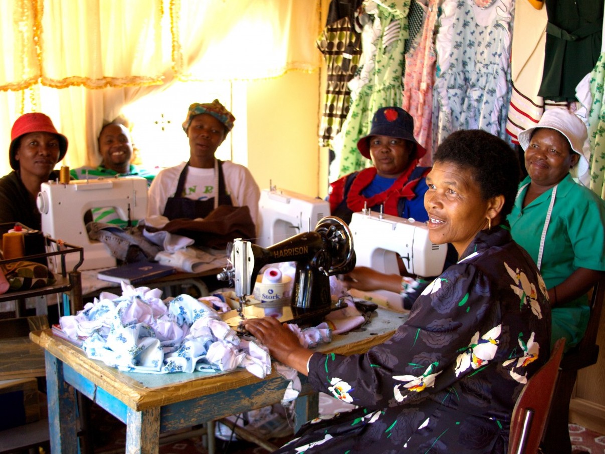 A group of female members of a Self Help Group sitting with their sewing machines.
