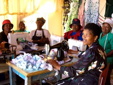 A group of female members of a Self Help Group sitting with their sewing machines.