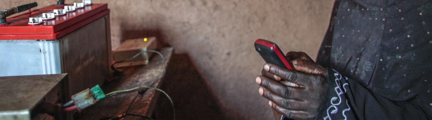 Maida holding a phone | Phone charger | Agatare, Rwanda